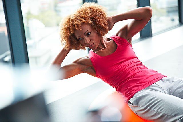 Frau macht Sit-Ups in einem Fitness First Studio