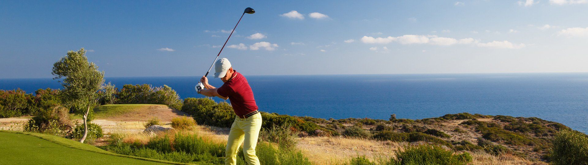 Golfspieler beim Abschlag auf Mallorca, im Hintergrund das Meer