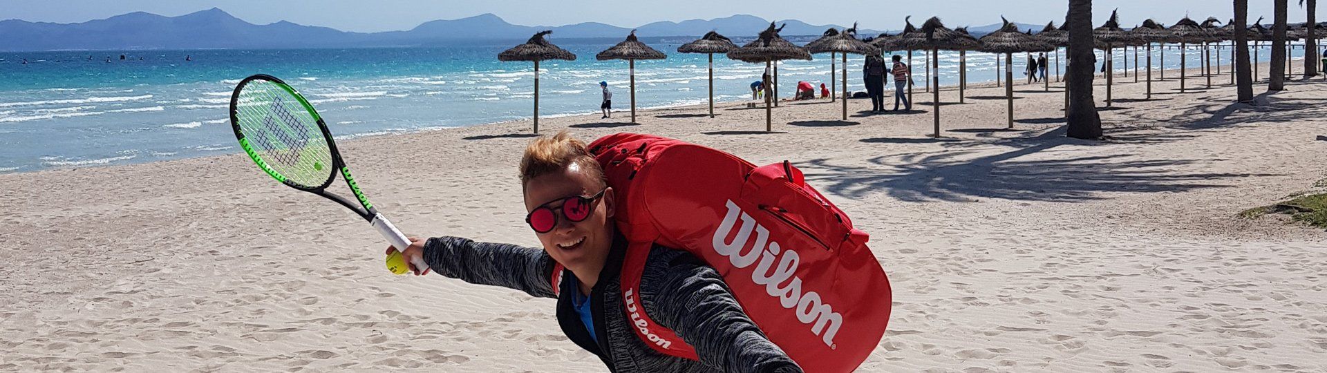 Tennislehrer vor toller Strandkulisse mit Sonnenschirmen