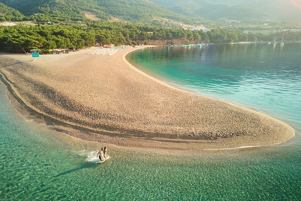 Zwei Menschen laufen im flachen Wasser am Strand entlang